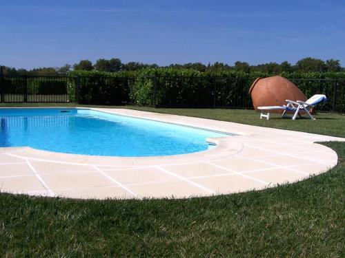 - une piscine sur gazon avec une chaise à côté dans l'établissement Charming farmhouse gite in southwestern France, à Montferrand