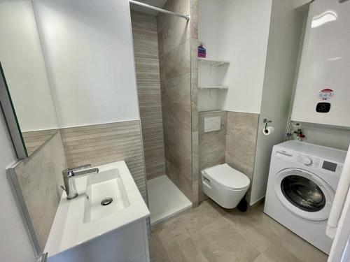 une salle de bain avec un lavabo et une machine à laver dans l'établissement Studio, Trestraou Beach, Perros Guirec, à Perros-Guirec