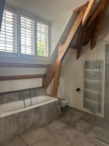a attic bathroom with a tub and a toilet at African Cosy suite in The Hague