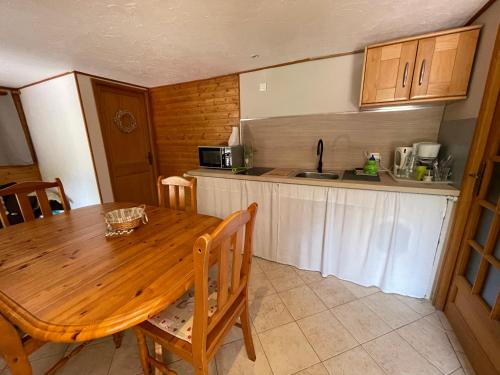une cuisine avec une table en bois, des chaises et un évier dans l'établissement la terrasse, à Saint-Étienne-de-Tinée