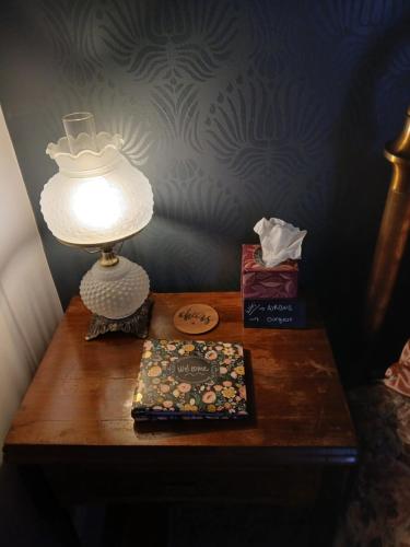 a table with a lamp and a book on it at The Bissing House in Hays