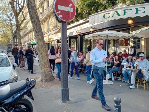 un homme passant devant un panneau de rue devant un café dans l'établissement heart of Marais ,center,romantic and gorgeous appartement, 1 minute metro ,close to Eiffel tour and Louvre meusm, à Paris