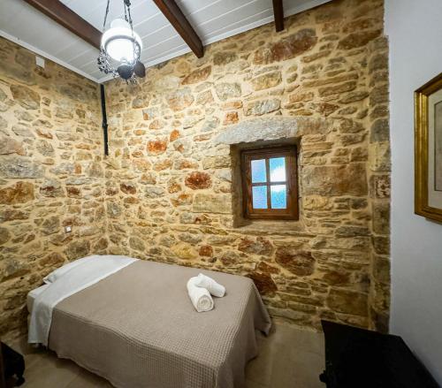 a bedroom with a bed and a stone wall at One&Only Kalamoti Gem Retreat in Kalamoti