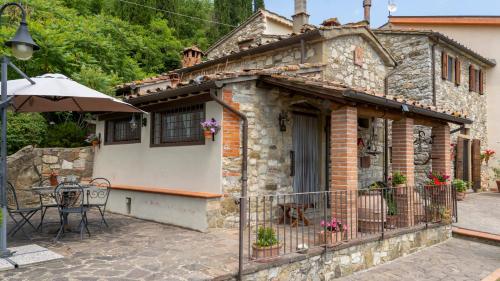 a stone house with a table and an umbrella at Il Borghetto di Carra in Talla