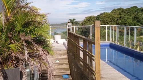 a wooden walkway leading to a balcony with a pool at Pousada Las Piedras in Praia do Rosa