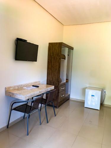 a room with a table and a tv on a wall at Chalés Lampião in Piranhas