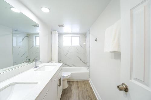 a white bathroom with a sink and a toilet at Coastal Escape Walk to Beach Pool and Gym in Boca Raton