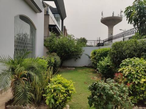 a garden in front of a building with a tower at Luxury Villa - 1 Kanal Furnished 5 bedrooms , DHA Phase 6 in Lahore