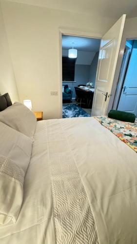 a bedroom with a large white bed and a desk at Emerald dream house in Swindon
