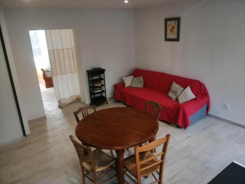 un salon avec un canapé rouge et une table dans l'établissement Gîte calme bercé par le bruit du ruisseau, à Arinthod