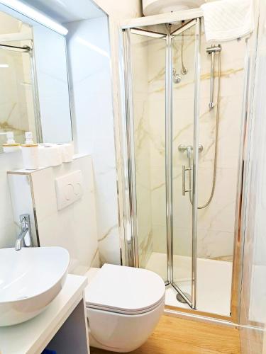 a bathroom with a shower and a toilet and a sink at Apartments & Rooms Čakelić in Mlini