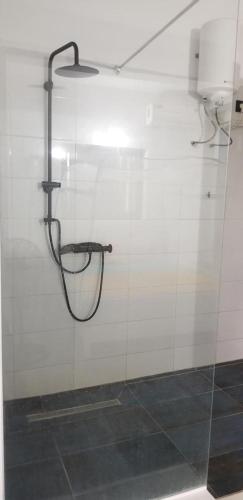 a shower in a bathroom with a white tiled wall at La croix du sud in Lomé