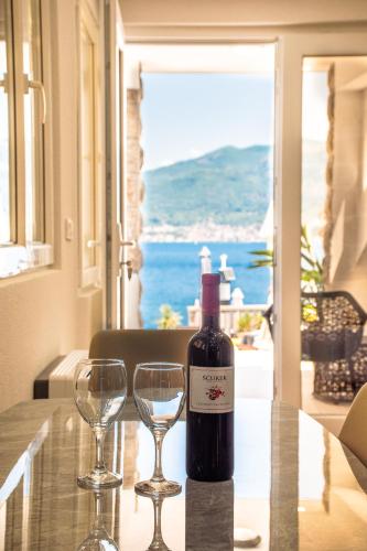 a bottle of wine sitting on a table with two wine glasses at Apartments Kostic- Sea view in Tivat