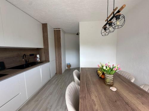 a kitchen and dining room with a wooden table with flowers at Apartman Perla in Gornji Kraj