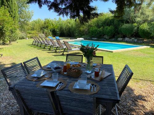 - une table en bois avec de la nourriture à côté de la piscine dans l'établissement Mas des Alpilles au cœur de la nature avec piscine, à Maussane-les-Alpilles