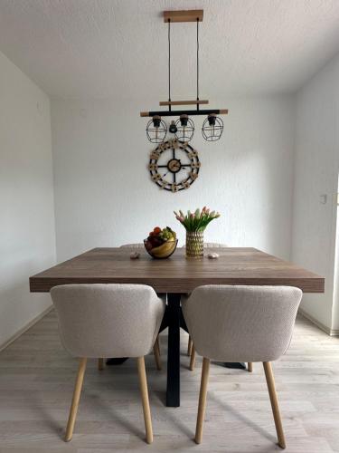 a dining room table with two chairs and a chandelier at Apartman Perla in Gornji Kraj