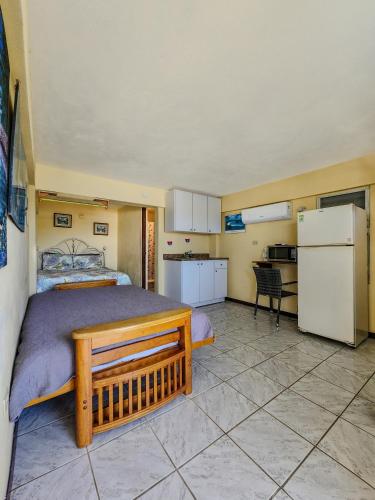 a bedroom with a large bed and a kitchen at Casa Robinson Guest House in Culebra