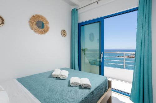 a bedroom with a bed with a view of the ocean at Finikas Resort Sfakia - Seaside Rooms in Loutro