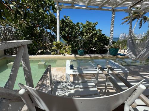 a hammock and chairs next to a swimming pool at Casa Arsha Beachfront Bed & Breakfast in Dzidzantún