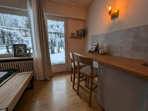 une cuisine avec un comptoir, une table et une fenêtre dans l'établissement Au Petit Bois, à Chamonix-Mont-Blanc