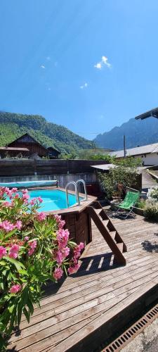 une terrasse en bois avec une piscine et des fleurs dans l'établissement Studio en Abondance, à Vacheresse
