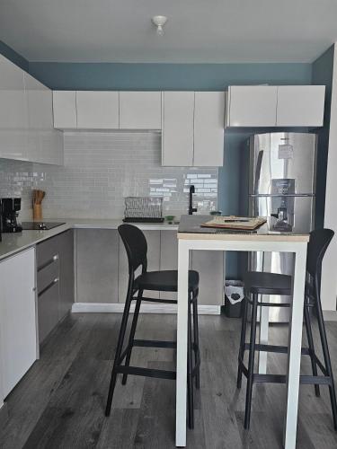 a kitchen with white cabinets and black bar stools at Chic Studio in Barrio Escalante in Tapantí
