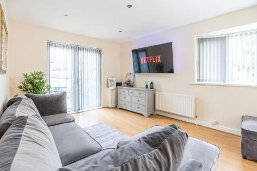 a living room with a couch and a tv at Pinfold Court Apartments in Knowsley