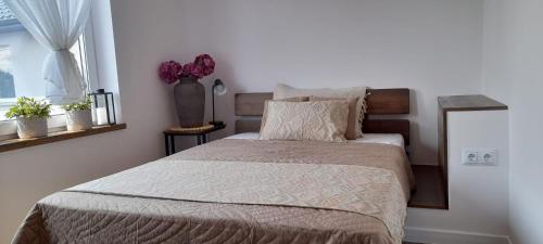 a bedroom with a bed and a vase with flowers at Apartamenty Nadmorskie lofty in Gąski