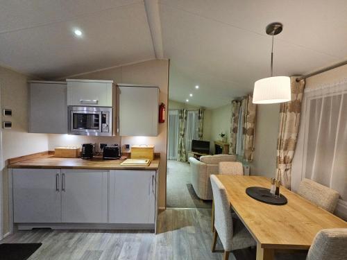 a kitchen and living room with a table and a room at Robins Sunset Holiday Home in Seasalter