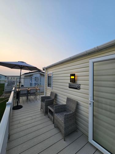 a deck with a table and chairs and an umbrella at Robins Sunset Holiday Home in Seasalter