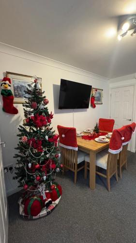 a dining room with a christmas tree and a table at Orchid Cotswold Stone house in Swindon