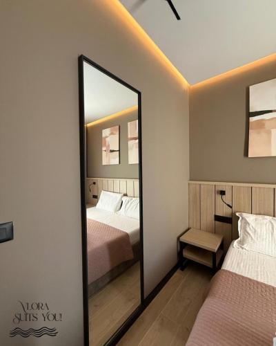 a mirror in a bedroom with two beds at Apandnrosm in Vlorë