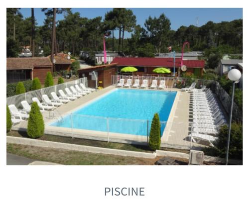 - une piscine avec des chaises blanches dans l'établissement Mobil home tout confort 6 personnes, à Lacanau