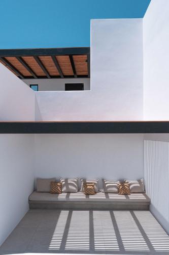 a bench sitting on a white wall with a roof at Noir Mykonos in Mýkonos City