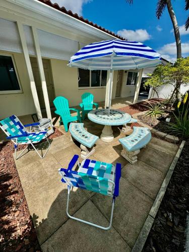 Un patio con sillas, una mesa y una sombrilla. en Renew Apart - Our Home Pompano, en Pompano Beach