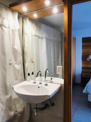 a white sink in a bathroom with a shower at Apart Hotel Robles del Sur in San Martín de los Andes