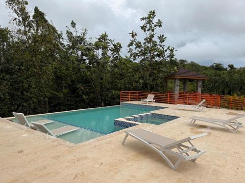 a swimming pool with chairs and a gazebo at VILLA LEMON Samaná in El Limón