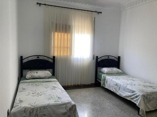 two beds sitting in a room with a window at Tetuán 2025 in Tetouan
