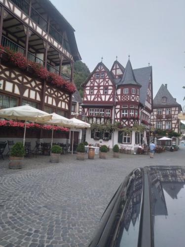 a group of brown and white buildings with tables and umbrellas at 100 Stufen über dem Rhein in Oberwesel