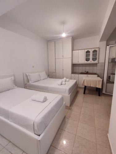 a white room with two beds and a kitchen at Villa Sidorela in Ksamil