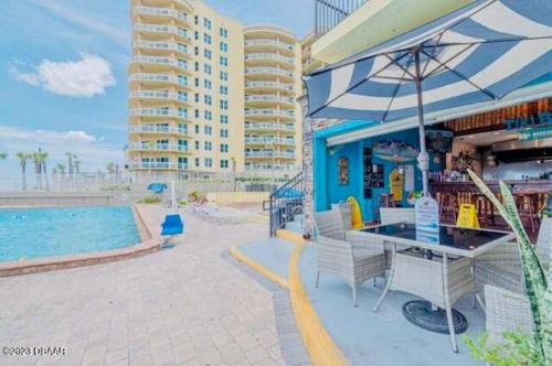 un complejo con piscina y mesa con sombrilla en Direct beach access 1st Floor walkout w/kitchen, en Daytona Beach
