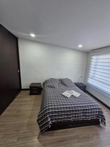 a bedroom with a bed with a plaid blanket at Apartamento La Floresta con todas las comodidades in Bogotá