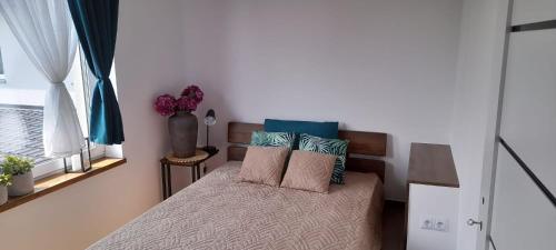 a bedroom with a bed with pillows on it at Apartamenty Nadmorskie lofty in Gąski