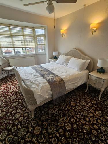 a bedroom with a large bed and two windows at 4 bed detached house near Manchester Airport Manchester -Cheadle in Cheadle