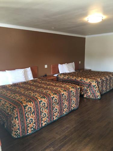 two beds in a hotel room with two bedsskirtspectspectssenalsenalsenalsenal at colfax motorlodge in Colfax