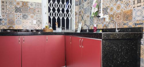 a kitchen counter with red cabinets and a sink at Hostel em Brusque - para quem busca economia - Ótima localização in Brusque