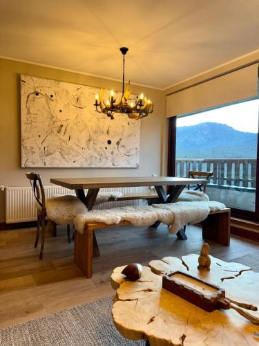 a dining room with a table and a large window at Departamentos Exclusivos Termas de Chillán in Nevados de Chillan