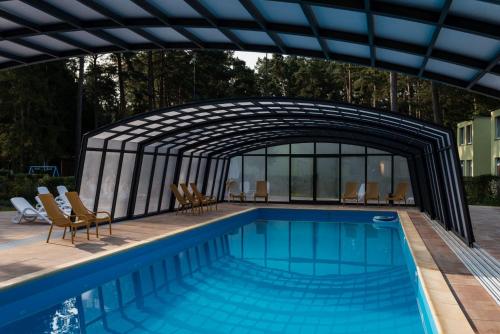a swimming pool with a retractable structure next to a building at OW Krakus I - pokoje i domki in Stegna