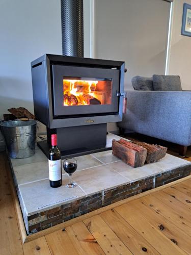 a fireplace with a bottle of wine and a glass at Paradise by the Beach - Culburra beach in Culburra Beach