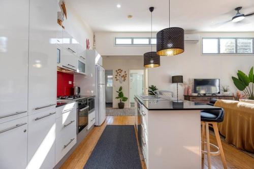 a kitchen with white cabinets and a kitchen island at Delightful Dicky Beach Holiday House in Caloundra